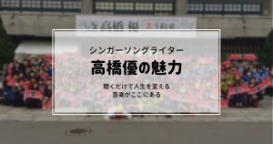 白い横断幕が掲げられた建物の前でのぼやけた集合写真。オーバーレイされた日本語のテキストは次のようになります。シンガーソングライター・秋田音楽大使 高橋優の魅力、聴くだけで人生を変える音楽がここにあります。.
